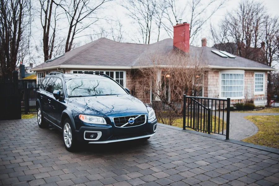 An estate car parked on a brick driveway outside a house
