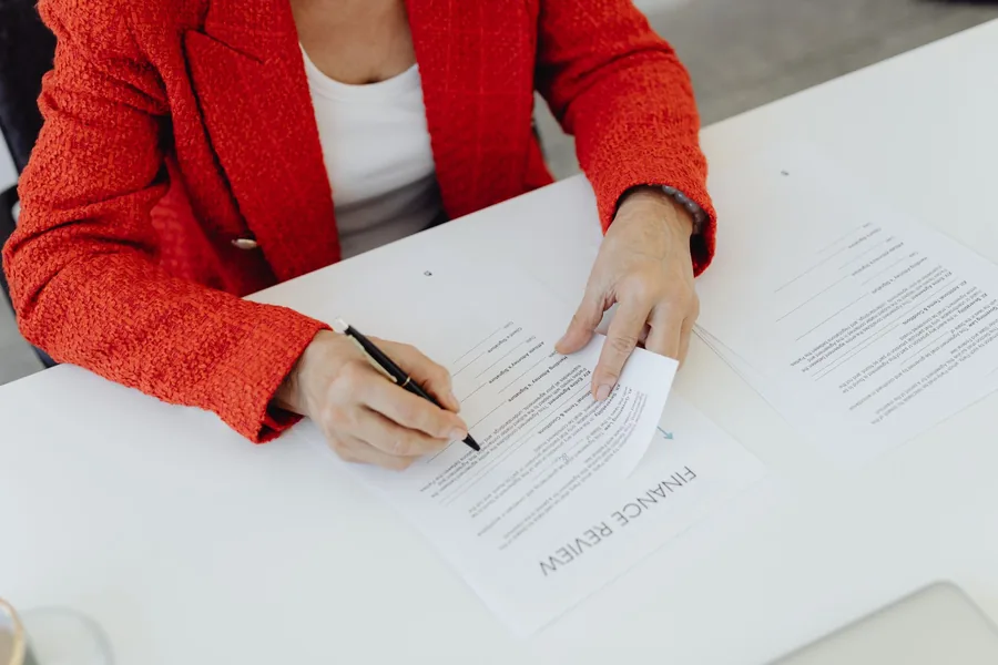 Close-up of hands signing a finance agreement at a desk