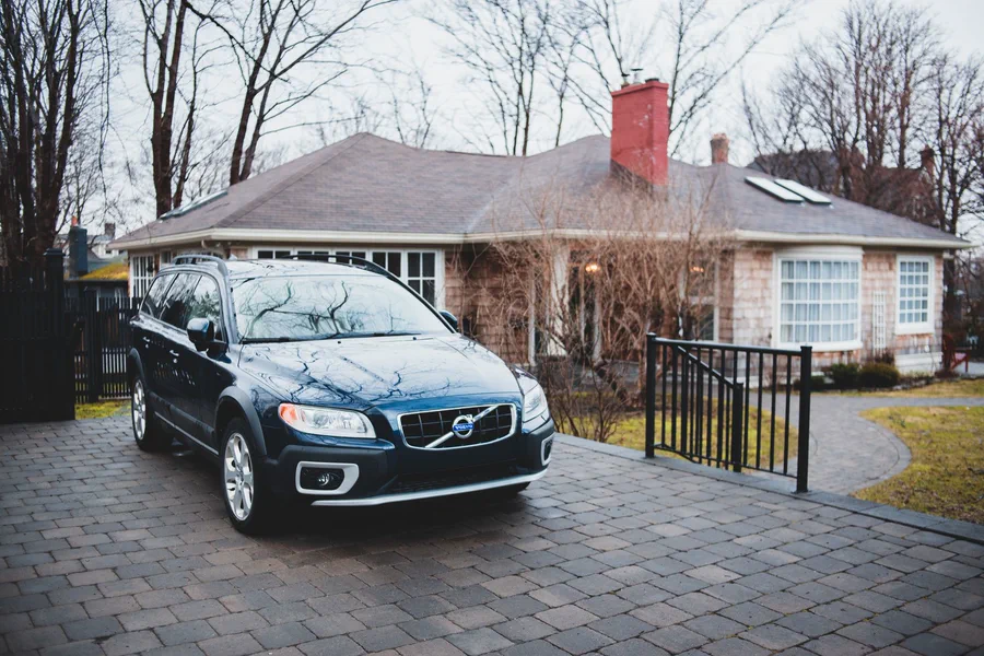 A car parked on a suburban driveway in front of a house