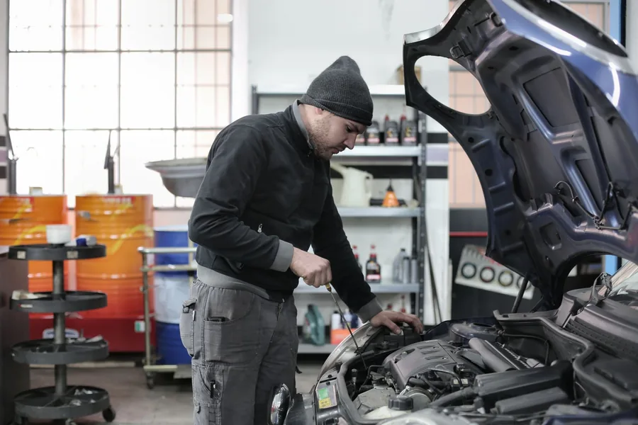A mechanic inspecting the engine bay of a car in a garage