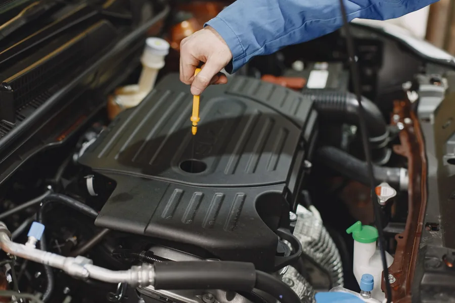 A hand pulling the yellow dipstick out of an engine bay to check the oil level