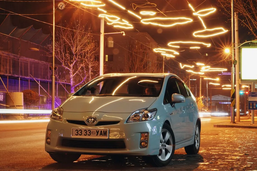 A Toyota Prius hybrid car on a city street in the evening