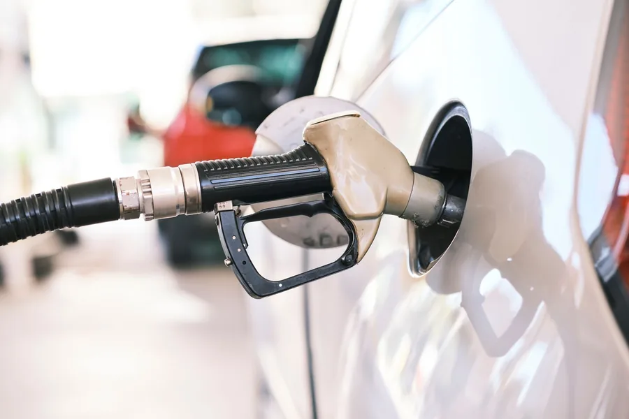 A fuel nozzle inserted into a car's filler neck on a forecourt
