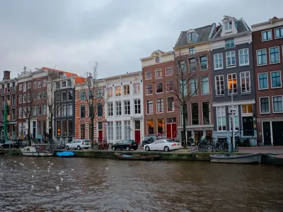 Canal houses in Amsterdam with cars and bicycles parked along the quay