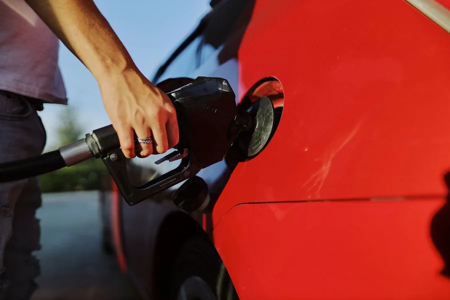 A fuel nozzle being inserted into the filler neck of a car