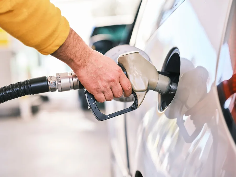 A fuel nozzle being inserted into the filler neck of a car at a filling station
