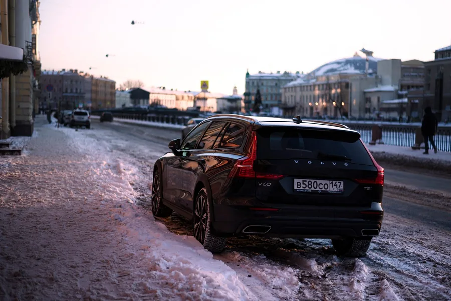 A dark Volvo estate parked on a snow-covered street in a Swedish city in winter