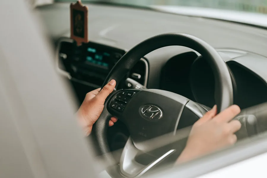 A driver's hands resting on the steering wheel of a car