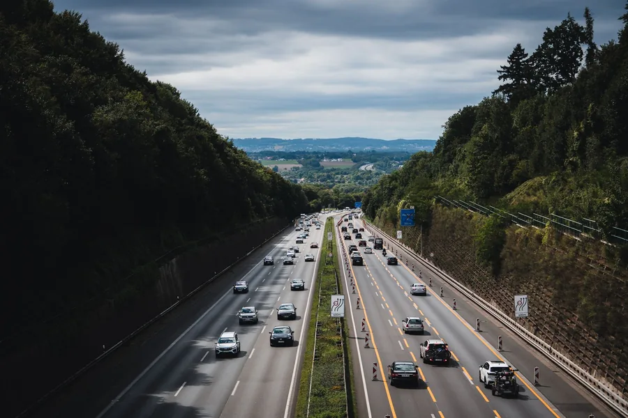 Traffic on a multi-lane motorway cutting through wooded hills