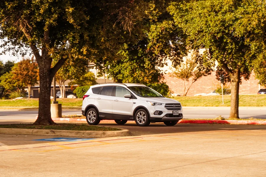 A white compact crossover SUV parked outdoors in autumn