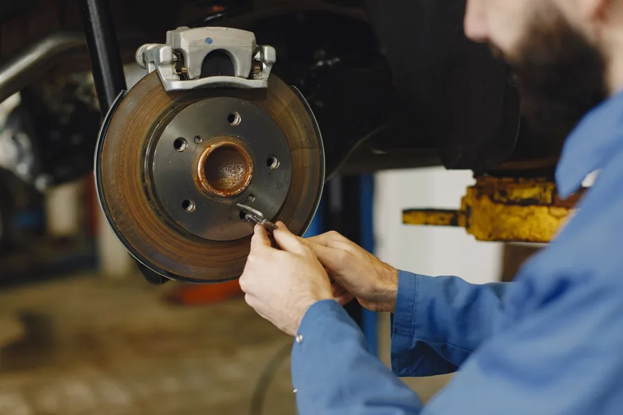 Close-up of a mechanic working on a car brake disc with the wheel removed