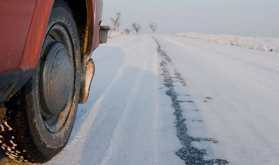 Close-up of a car tyre packed with snow on a snow-covered winter road