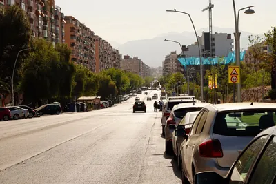 A wide Spanish city avenue lined with parked cars and apartment blocks
