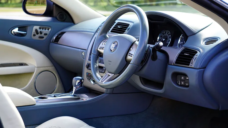 Two-tone blue and cream leather car interior with the steering wheel and dashboard in view