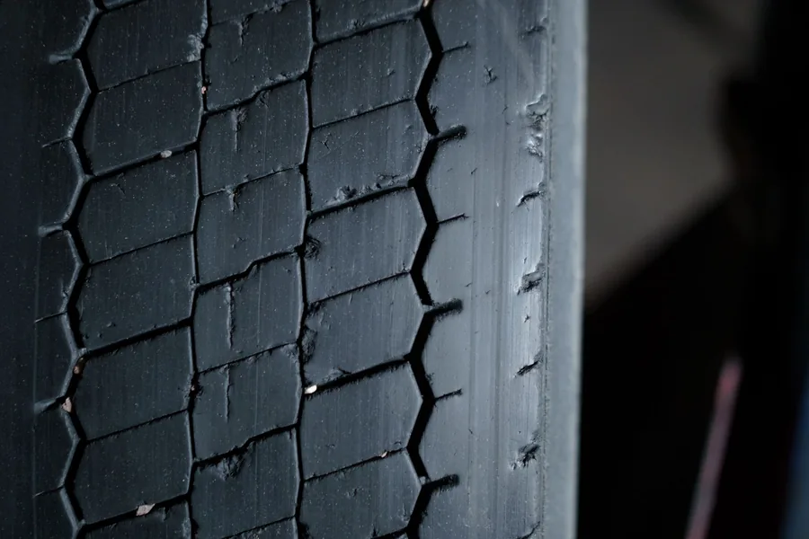 Close-up of worn tyre tread on a car wheel, showing the grooved rubber surface