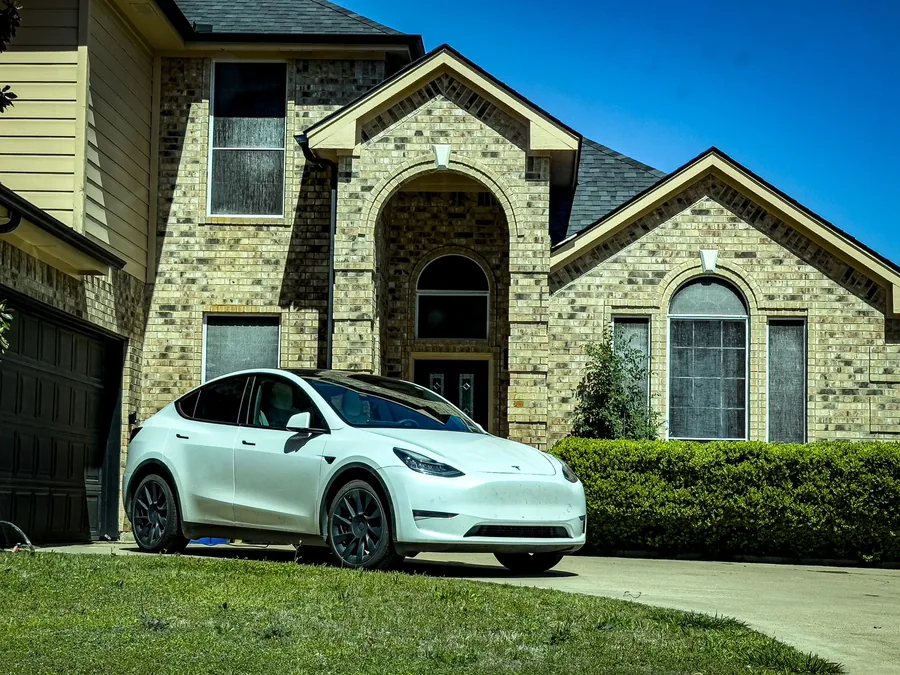 An electric car parked on a driveway outside a house
