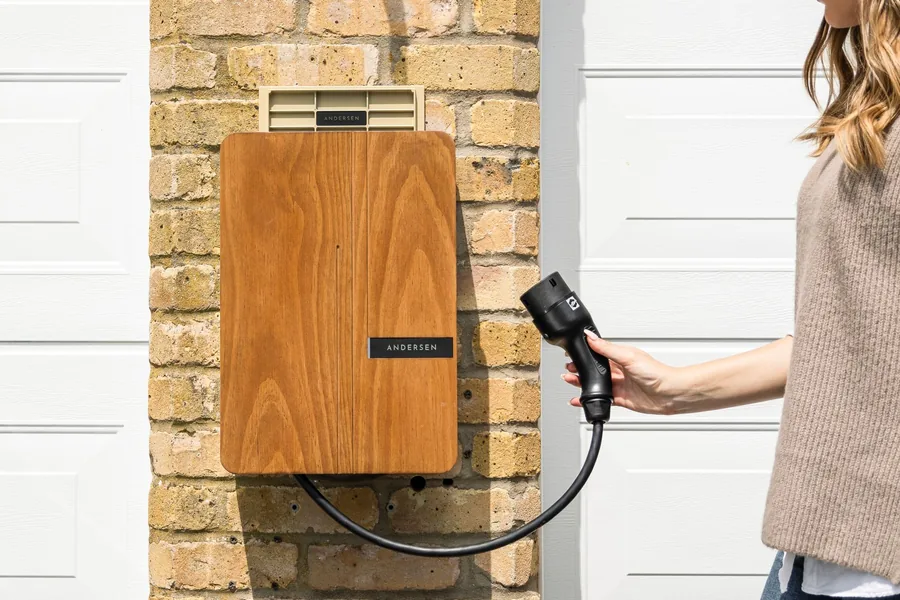 A wall-mounted home EV charging unit fitted to a brick wall outside a house