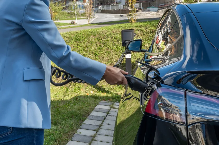A driver connecting a charging cable to an electric car