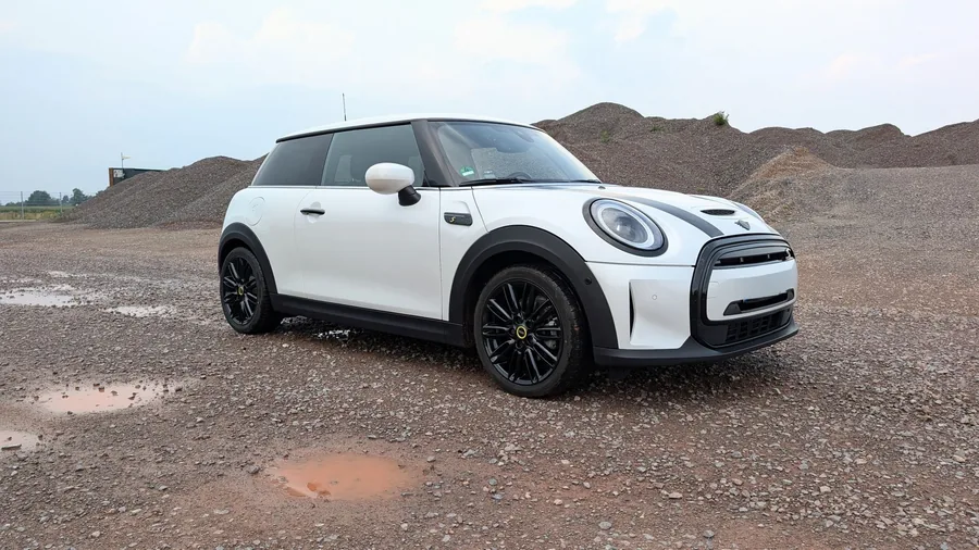 A Mini Cooper parked on a gravel lot under a clear sky