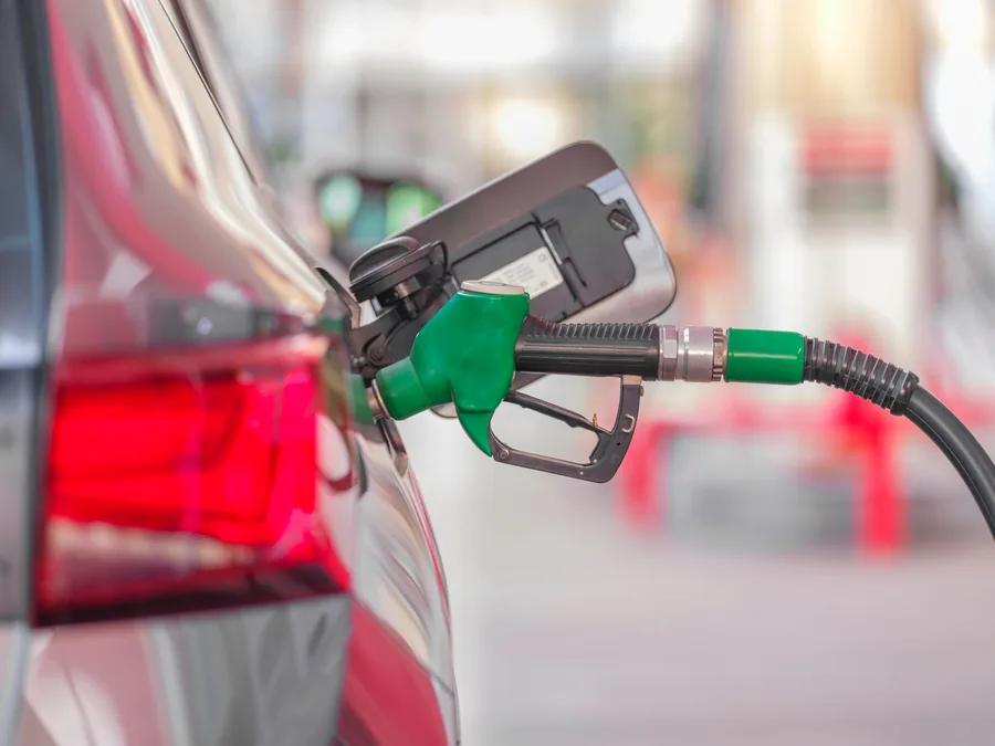 A fuel nozzle inserted into the filler neck of a car at a filling station