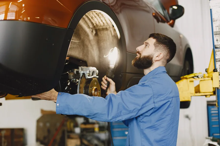 A mechanic inspecting the brakes of a car raised on a lift
