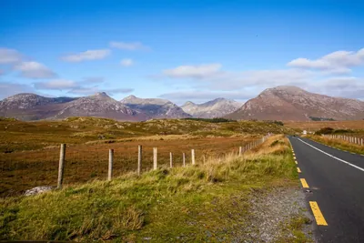 A rural road winding towards mountains in the west of Ireland