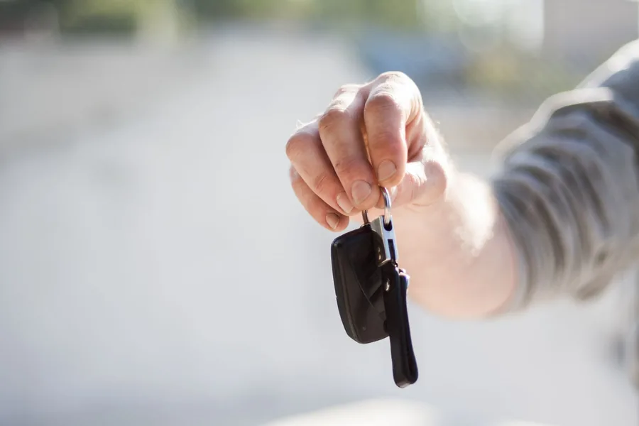 A hand holding a set of car keys before a private sale handover