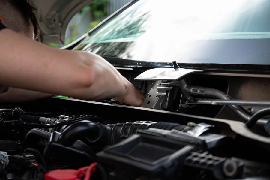 A person checking the engine bay of a car with the bonnet open