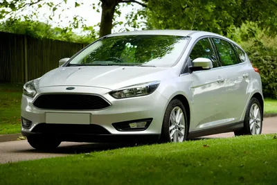 A silver hatchback parked on a leafy UK street with a blank front plate