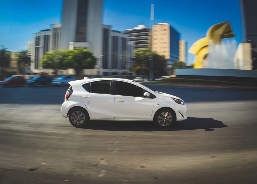 A white Toyota Prius hybrid driving on an urban road