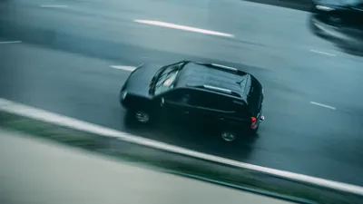 A dark car driving on a multi-lane highway
