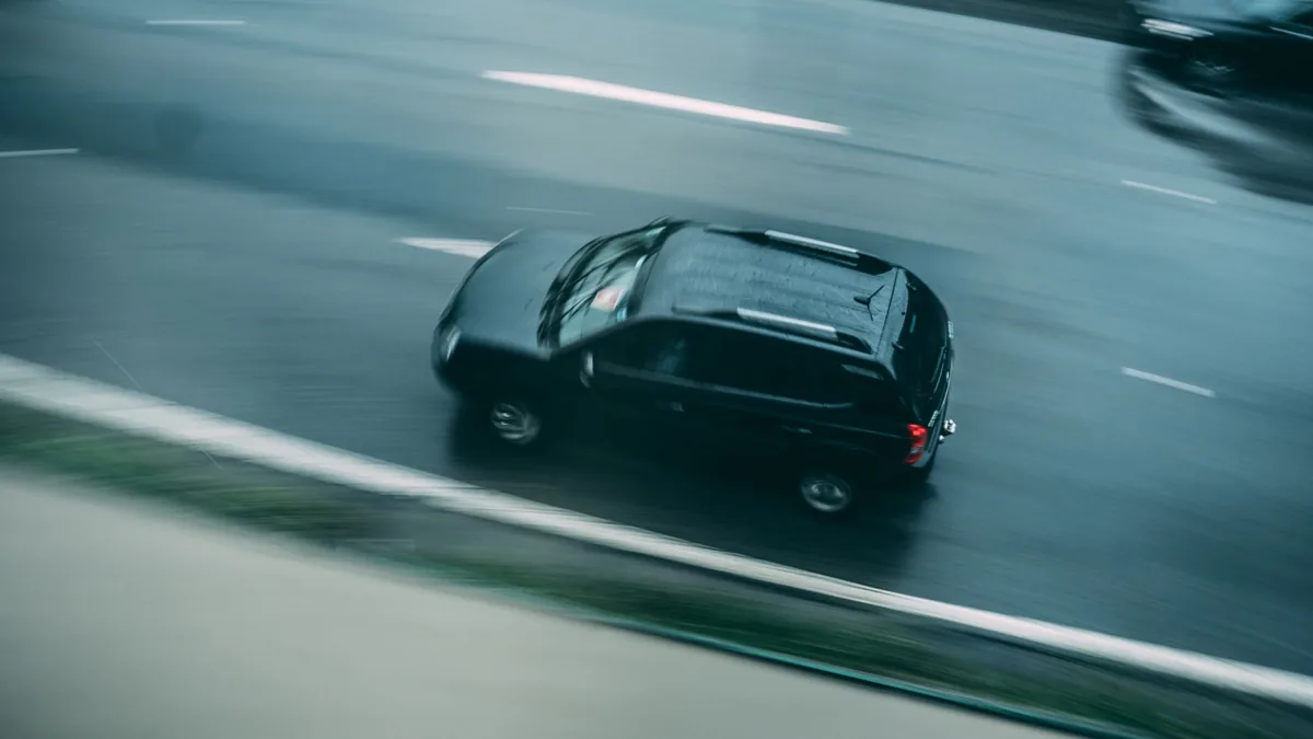 A dark car driving on a multi-lane highway