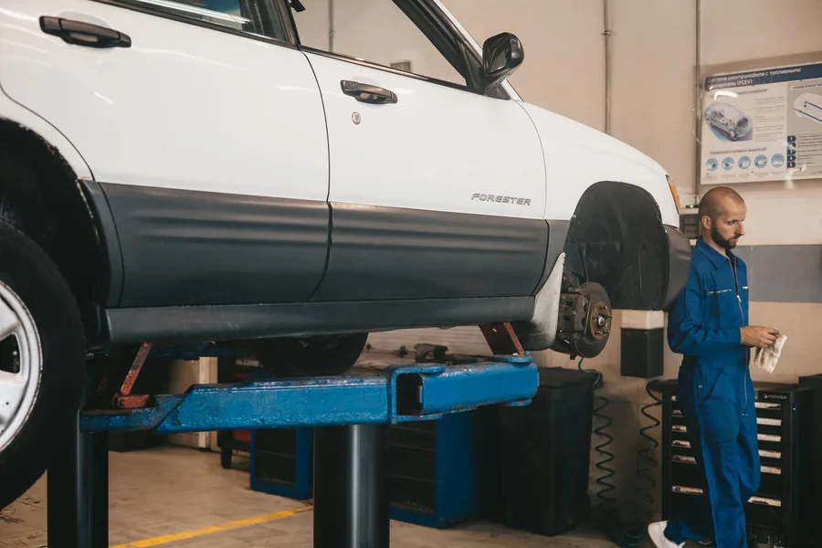 A mechanic inspecting a car raised on a lift in a workshop during a brake service