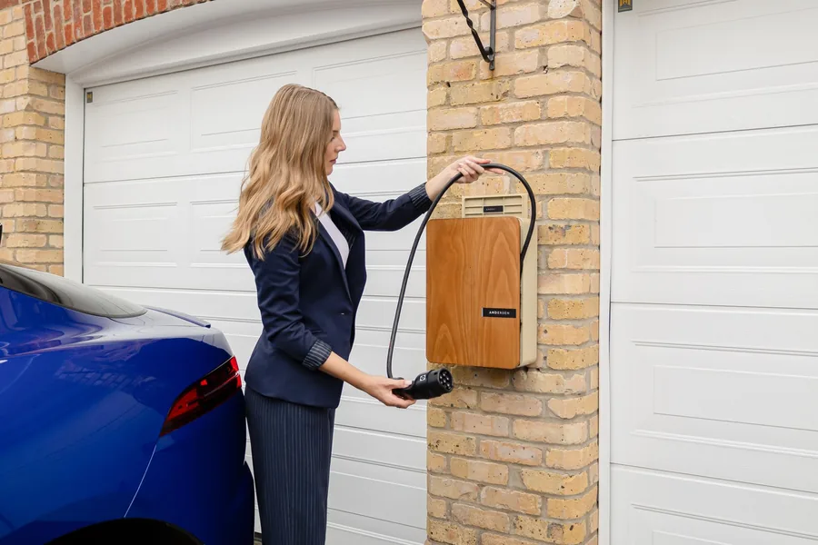A woman using a wall-mounted home EV charger in a domestic garage