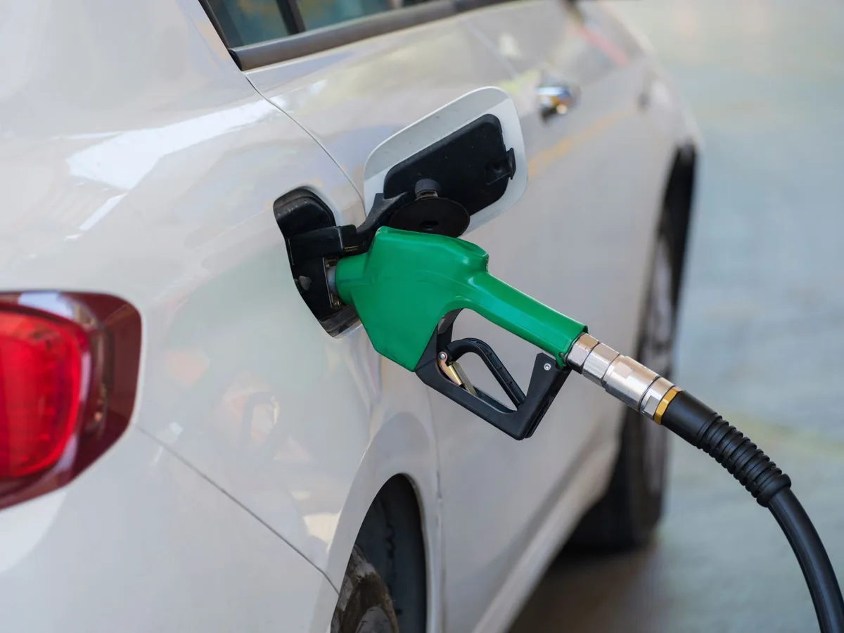 A fuel nozzle being inserted into the filler neck of a white car