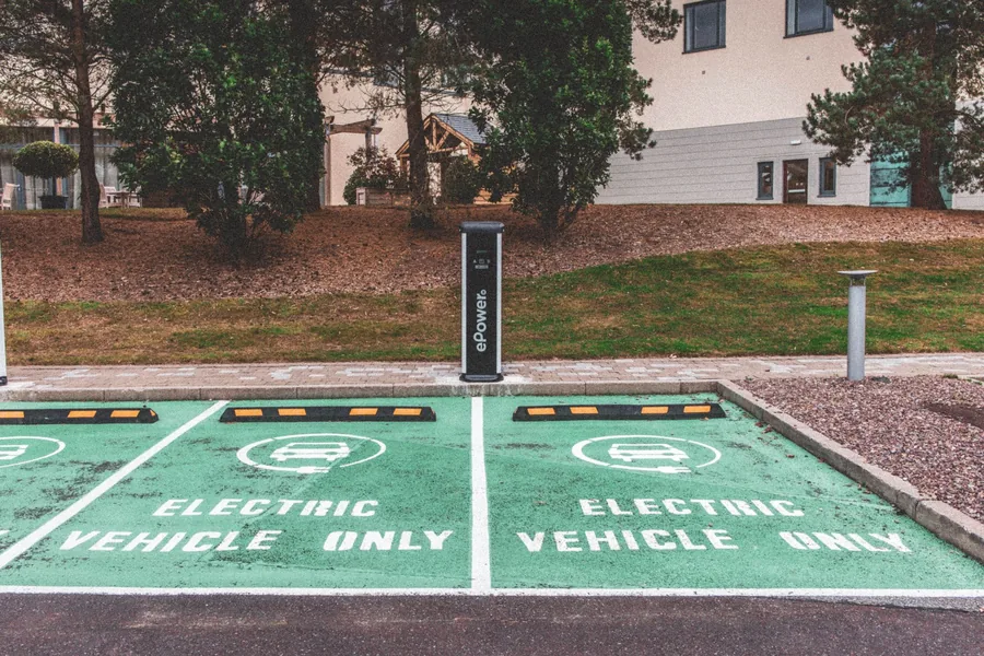 Parking bays painted green and marked electric vehicle only, with a shared charging post