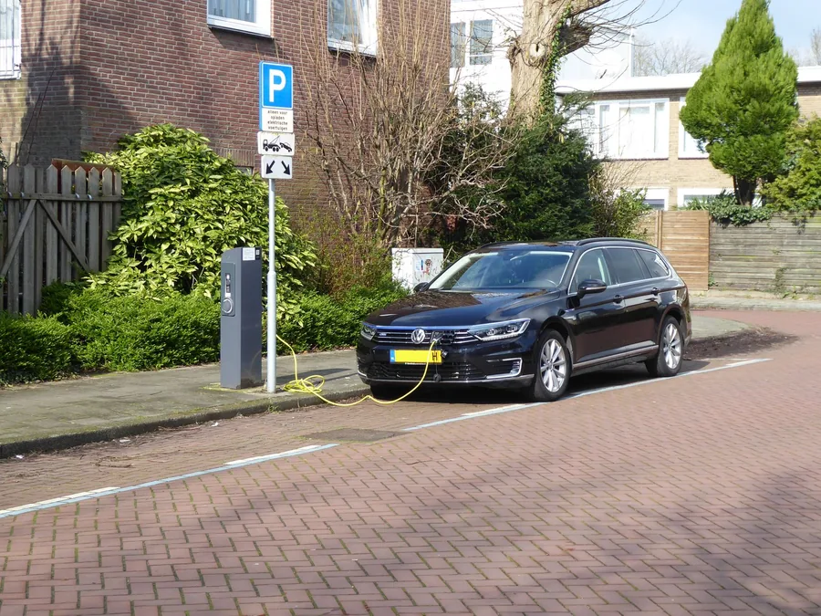 An electric car plugged into an on-street public charging bay in a European city