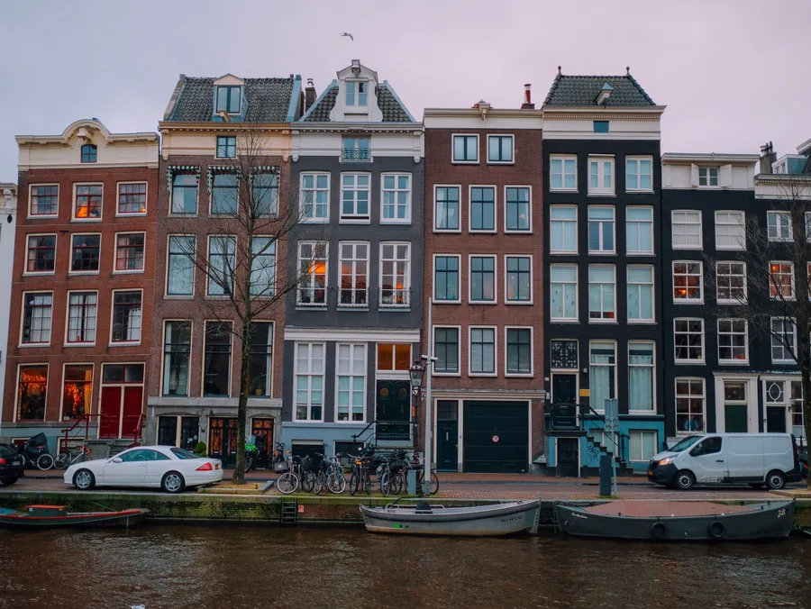 Narrow gabled canal houses reflected in the water in Amsterdam, Netherlands