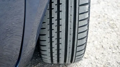 Close-up of a car tyre and wheel standing on a concrete surface