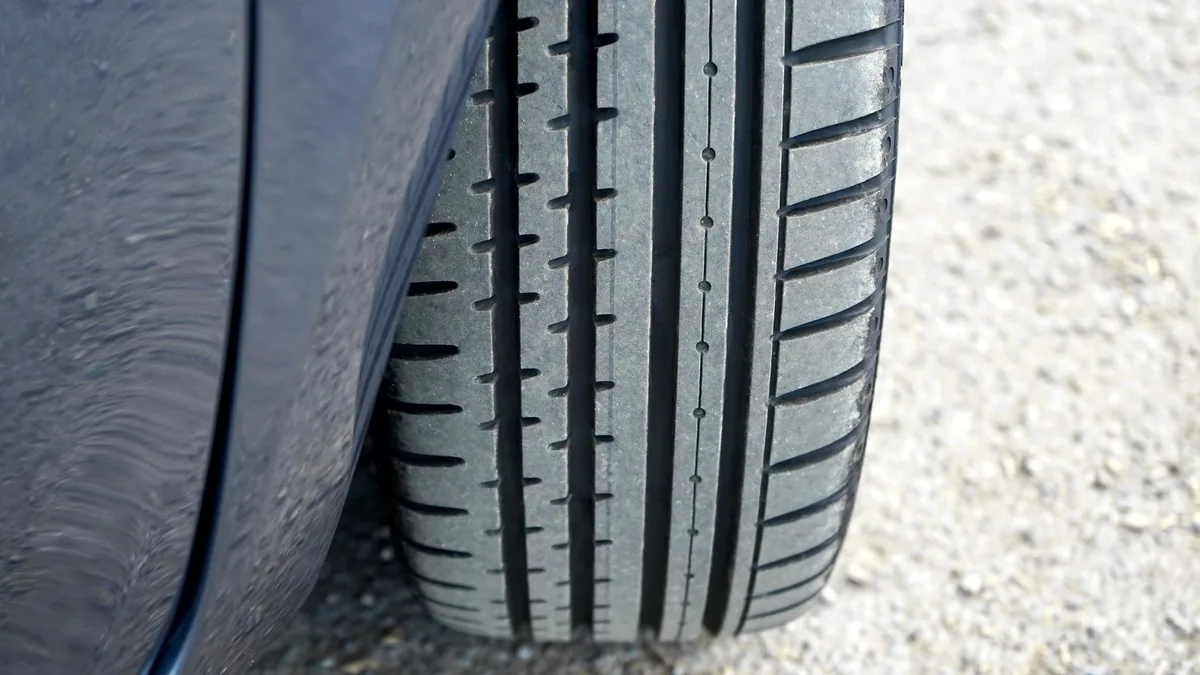 Close-up of a car tyre and wheel standing on a concrete surface