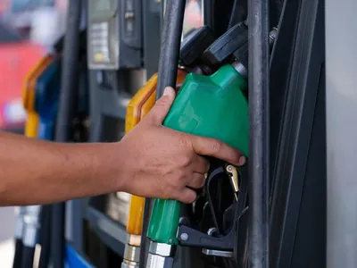 A hand holding a fuel nozzle at a petrol station pump
