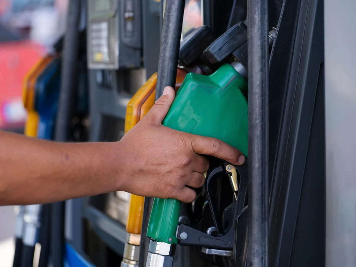 A hand holding a fuel nozzle at a petrol station pump