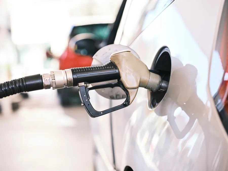 A fuel nozzle inserted into the filler neck of a car at a filling station