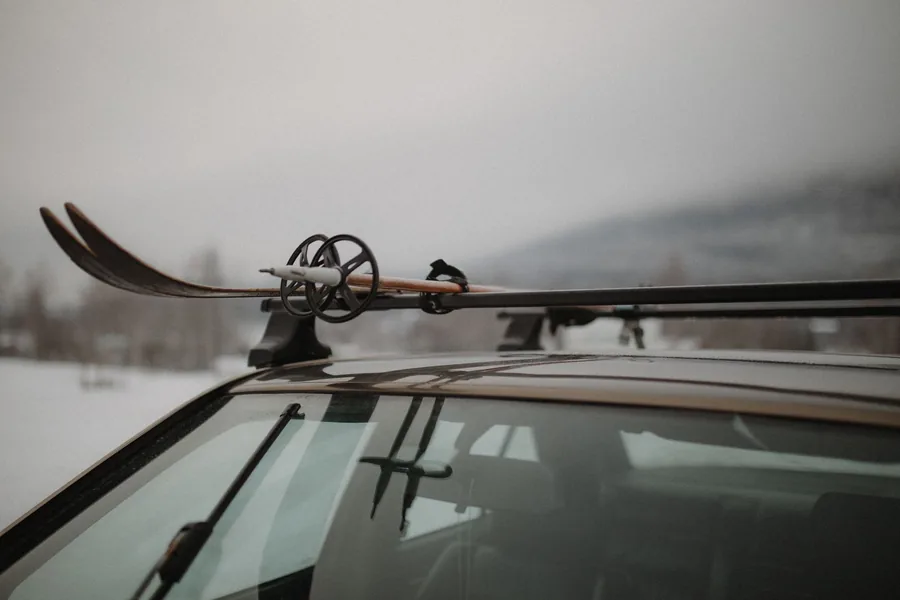 Skis and ski poles mounted on a car roof rack, adding frontal area above the windscreen